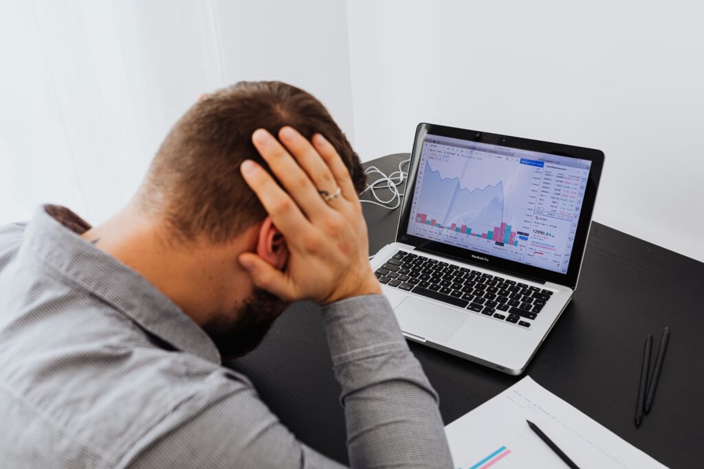 A businessman stressed by declining chart on his laptop.